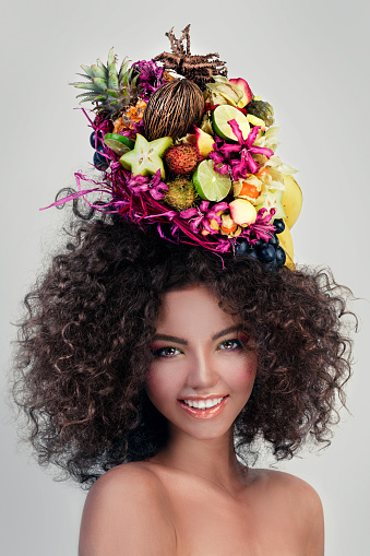 Close-up portrait of beautiful Cuban woman wearing hat decorated with fruits.