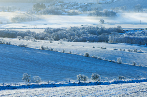 Looking across farmland and trees in heavy frost.