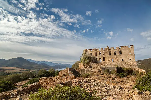 Derelict chateau of Pierre-Napoleon Bonaparte at Torre Mozza between Calvi and Galeria with mountains, coastline and blue skies in the background