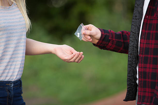 teenager-mädchen kauf von medikamenten aus den spielplatz von händler - drug dealer stock-fotos und bilder