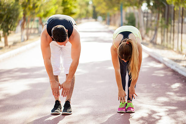 Stretching and touching toes Young couple in sporty outfit doing some stretching outdoors before jogging together toe stock pictures, royalty-free photos & images