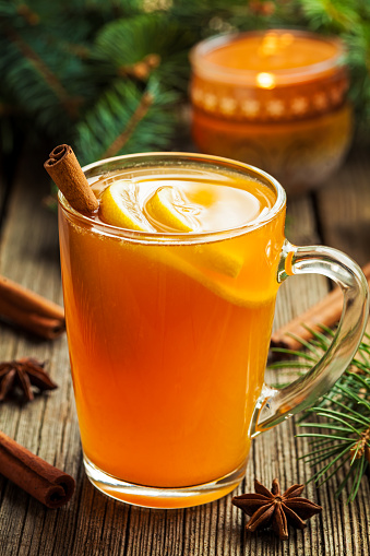 Traditional hot toddy winter drink with spices recipe. Healthy organic homemade holiday celebration beverage in glass. Vintage wooden background. Rustic style.