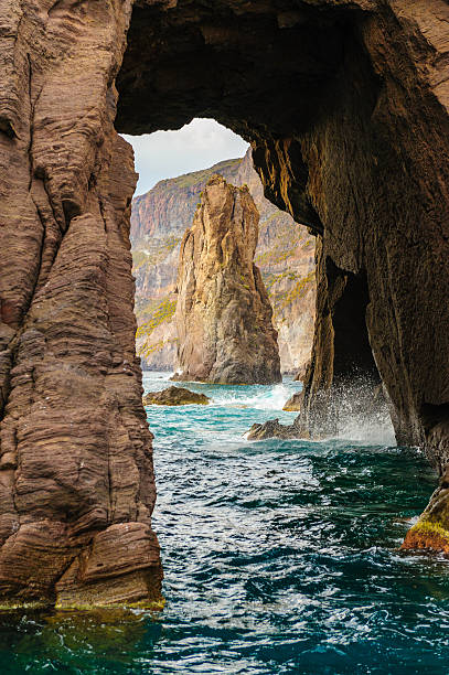 Waves among the rocks near Aeolian islands. Picturesque arch rock of Aeolian islands, Italy. filicudi stock pictures, royalty-free photos & images