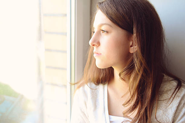 istock young beautiful brunette girl looking out the window 496489546