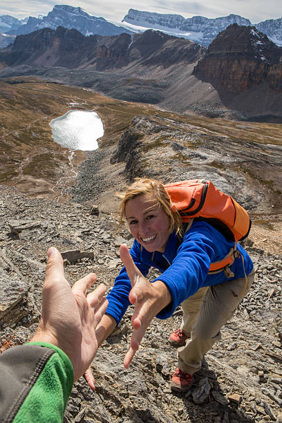 istock Young woman rock climbing, partner giving helping hand 496491668
