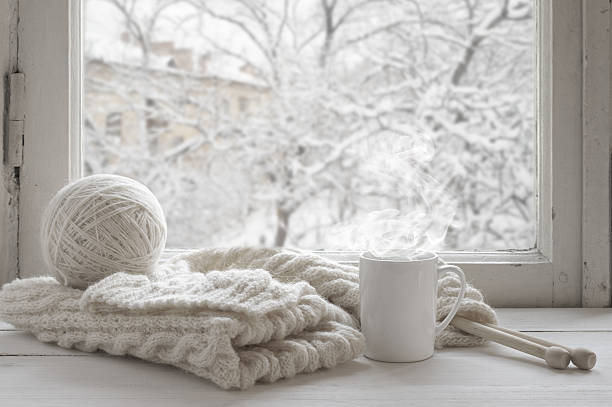 Cozy winter still life Cozy winter still life: mug of hot tea and warm woolen knitting on vintage windowsill against snow landscape from outside. knitting needle photos stock pictures, royalty-free photos & images