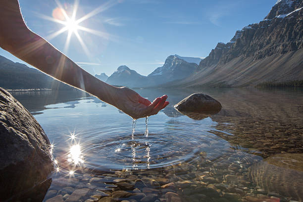 umani mano a pugno di prendere le fresche acque del lago - bow lake foto e immagini stock