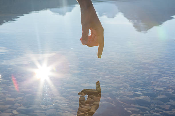 istock Finger touches surface of mountain lake 496494680