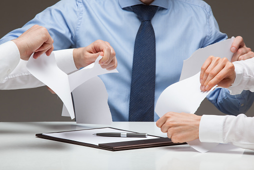 Business people cruelly tearing documents, gray background