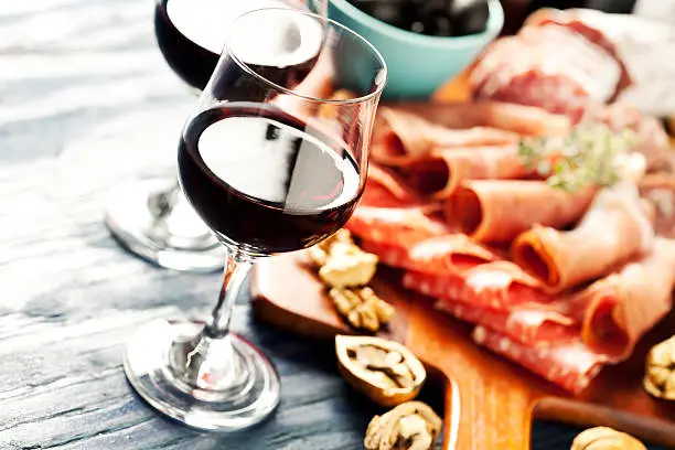 Red wine with charcuterie assortment on the background