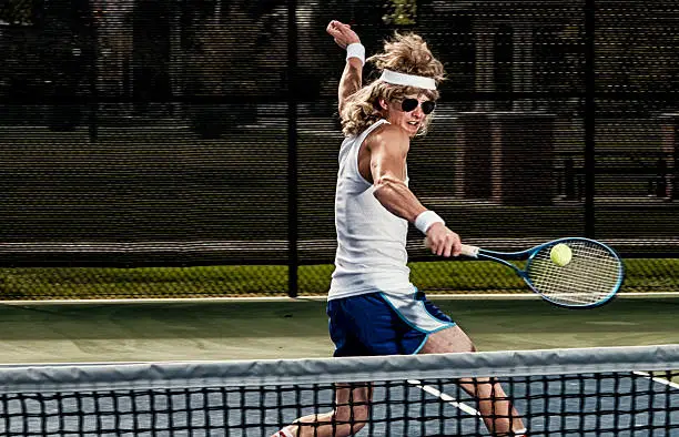 A retro 80's style guy playing tennis on a court.