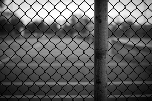 Black and white chain link fence background image with background blurred in a shallow depth of field.