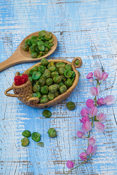 Dry green peas on cup and a wooden spoon.