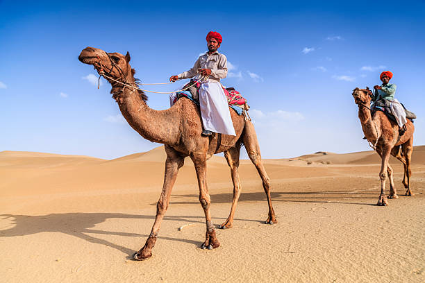 istock Indian men riding camels on sand dunes, Rajasthan, India 496547020