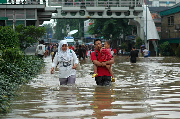 Crossing Flood Jakarta, Indonesia - January 19, 2014: Jakarta resident walk across the flooding street in Kampung Melayu, Jakarta, Indonesia. jakarta stock pictures, royalty-free photos & images