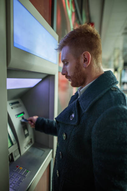 istock Young redhead businessman withdrawing money from ATM machine. 496554038