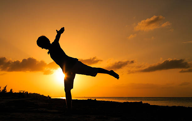 istock Silhouette of young man doing yoga at sunset 496554664
