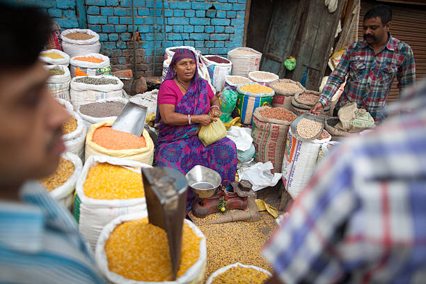 New Delhi, India - October 26, 2013.  An Indian woman sells various types of grains and lentils at the outdoor spice market in the old part of the city.