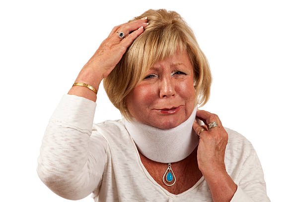 Women with neck brace in pain holding head and neck Attractive senior woman with blond hair wearing an orthopedic neck brace in obvious pain and discomfort with a very painful look on face grimacing, holding head and neck. Image shot on white background with studio strobes, Canon 5D Mark2 , 100 ISO, 24-115mm lens traction splint stock pictures, royalty-free photos & images