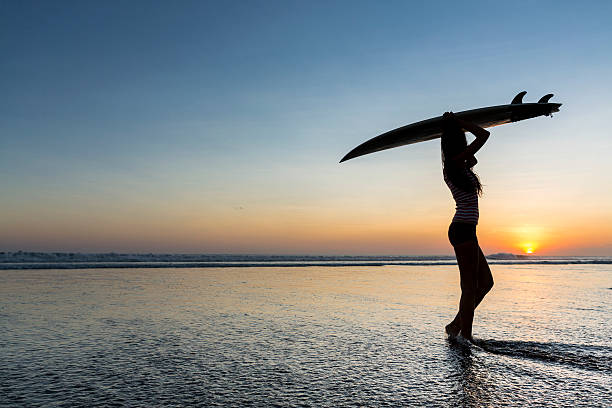istock Young female surfer at sunset by the sea 496565547