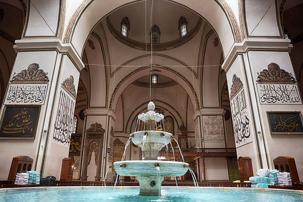 Fountain in Grand Mosque of Bursa, Turkey Bursa Grand Mosque or Ulu Cami was built between 1396 and 1399. The medieval drawings on the columns are arabic scripts which are words and verses from holy Quran. ulu camii stock pictures, royalty-free photos & images