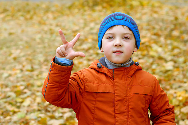 istock Boy in the orange jacket shows a sign 496572322