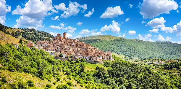 Beautiful view of idyllic village Castel del Monte, set into a steep hillside under apennine mountain peaks on a sunny summer day, Gran Sasso e Monti della Laga National Park, L'Aquila, Abruzzo, Italy