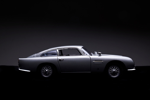 Beaconsfield, UK - November 2, 2015: A model of Aston Martin's iconic DB5 against a darkened background. Released in 1963, the car found global fame as the gadget-laden transport of the world's most famous secret agent, James Bond.