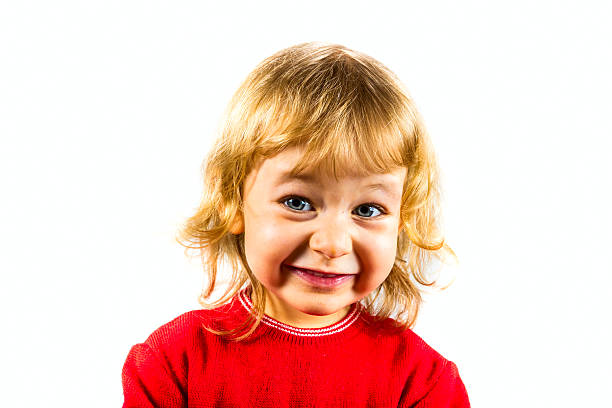 Headshot of a cheerful child smiling in nature with eyes closed.