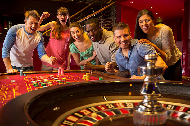 Friends Playing Roulette Group Of Friends Playing Roulette In Casino roulette photos stock pictures, royalty-free photos & images