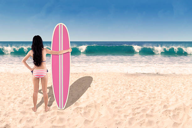 istock Beautiful young woman with surfboard 1 496590879