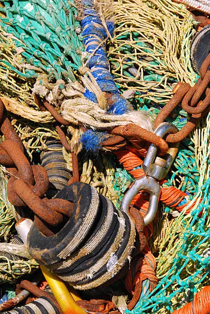 Full frame used fishing nets in a heap with twisted rope and block and Tackle..