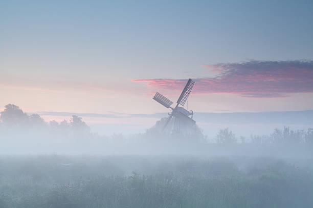 istock windmill in dense morning fog 496598931