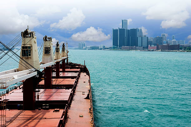 The Detroit skyline (enveloped in fog) as seen from across the Detroit River, in Windsor, Ontario, Canada.  A cargo ship navigates east along the river.
