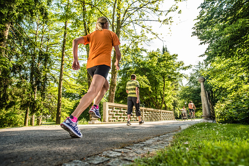 Senior woman jogging, man walking in park.