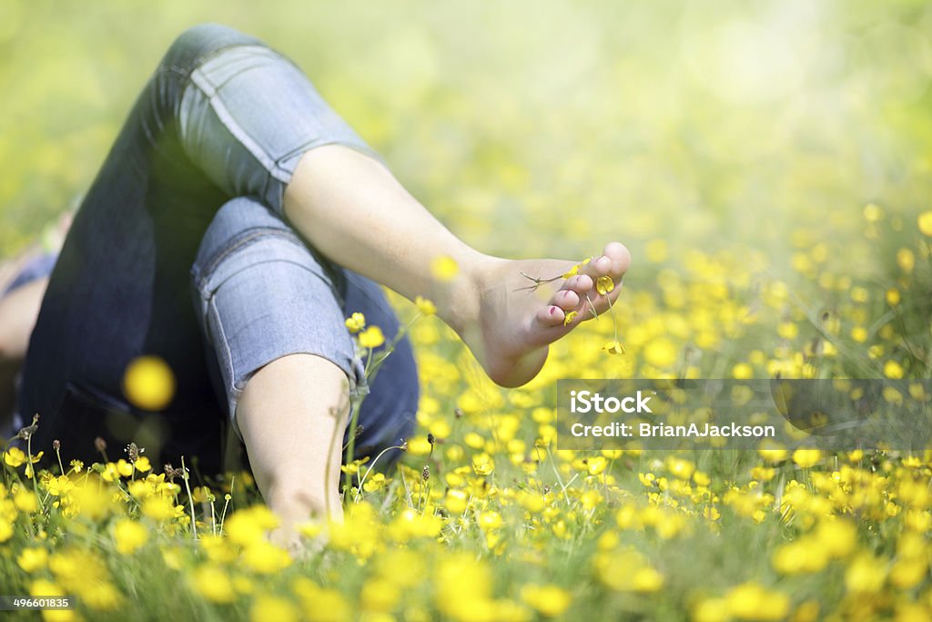 Woman lying in meadow relaxing Relaxing in a meadow full of buttercups in the summer sun Barefoot Stock Photo