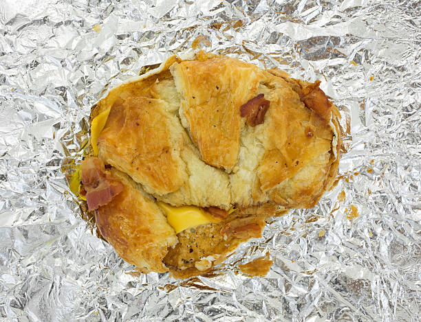 istock Bacon egg and cheese croissant breakfast sandwich on foil 496602416