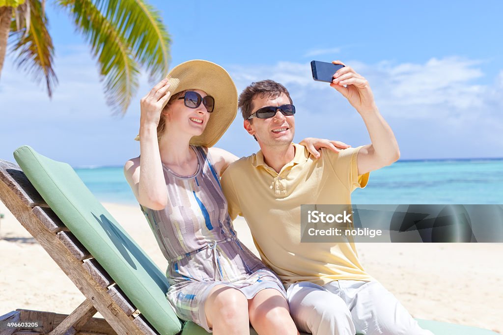 family taking photo positive smiling couple taking picture at the perfect beach Adult Stock Photo