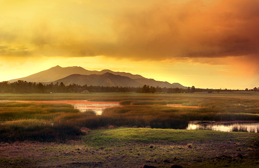 Mountains with beautiful sunset sky in Flagstaff Arizona during monsoon rains and fire season. Lake in foreground. Lots of copy space. Horizontal spread.