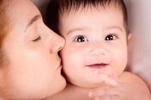 Beautiful mother kissing her adorable mixed race (Indian and Iranian) baby boy.