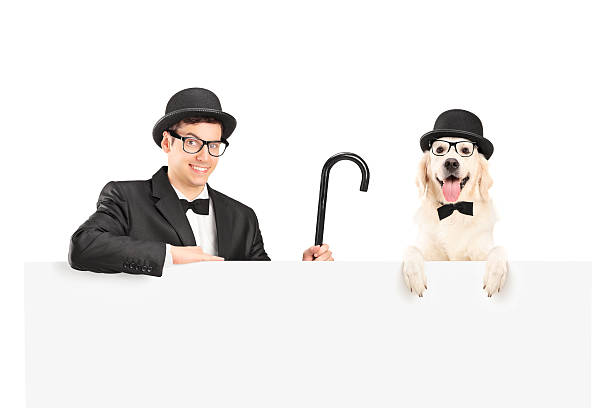 A performer in suit, retro hat and cane posing with dog behind a panel isolated on white