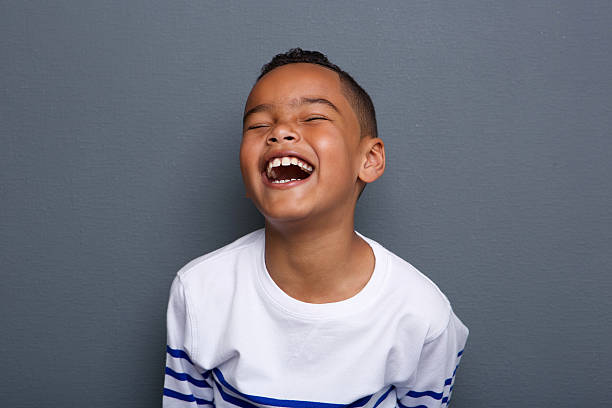 Excited little boy laughing Close up portrait of an excited little boy laughing on gray background staring photos stock pictures, royalty-free photos & images