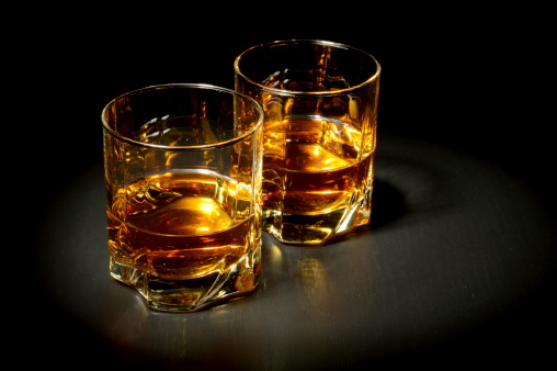 Two glasses of whiskey on black table