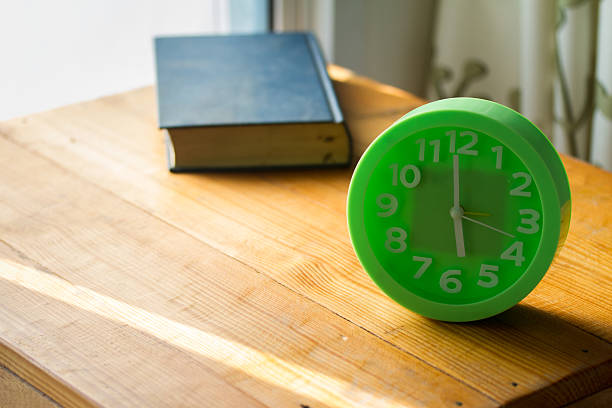 istock clock on table and old book, light enters the balcony, 496626406
