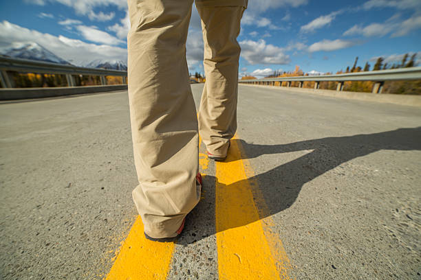 Person walking on empty highway-Focus on shoe