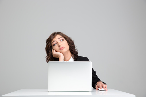 Thoughtful sad depressed curly pretty business woman dreaming sitting at the laptop