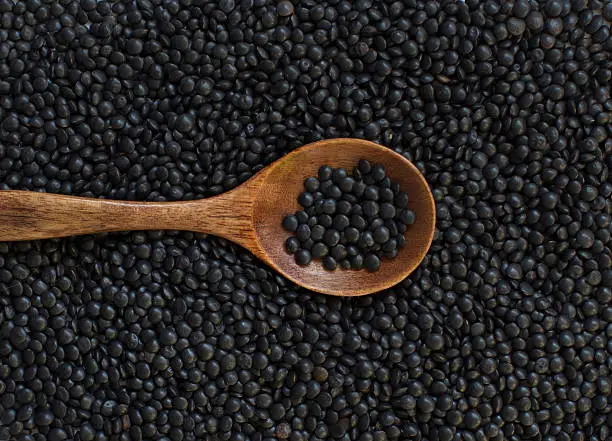 Pile of Black Lentils with a spoon top view