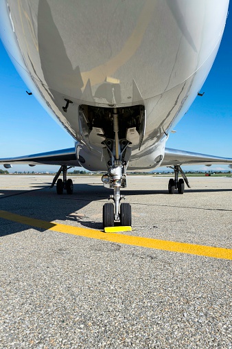 Close-up of the landing gear of a private jet on airport runway. Private airplane parked at the airport and preparation for next flight.