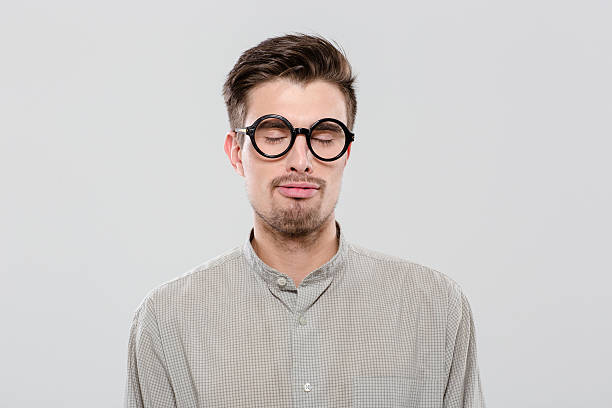 istock Young guy with closed eyes in black round glasses 496631832