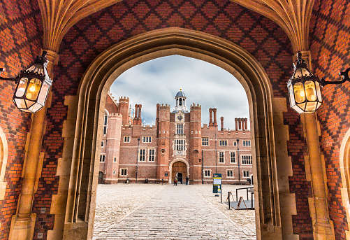 London, UK - 26 October, 2015: exterior image of Hampton Court Palace on a crisp autumn day. Hampton Court Palace is a royal palace in the London Borough of Richmond upon Thames, Greater London, in the historic county of Middlesex, and within the postal town East Molesey, Surrey. It has not been inhabited by the British Royal Family since the 18th century. The palace is 11.7 miles (18.8 kilometres) south west of Charing Cross and upstream of central London on the River Thames. Redevelopment began to be carried out in 1515 for Cardinal Thomas Wolsey, a favourite of King Henry VIII. In 1529, as Wolsey fell from favour, the King seized the palace for himself and later enlarged it. Along with St. James's Palace, it is one of only two surviving palaces out of the many owned by King Henry VIII. Horizontal colour image. 